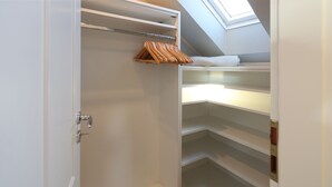 Ein begehbarer Kleiderschrank mit offenen Regalen und einer Kleiderstange.