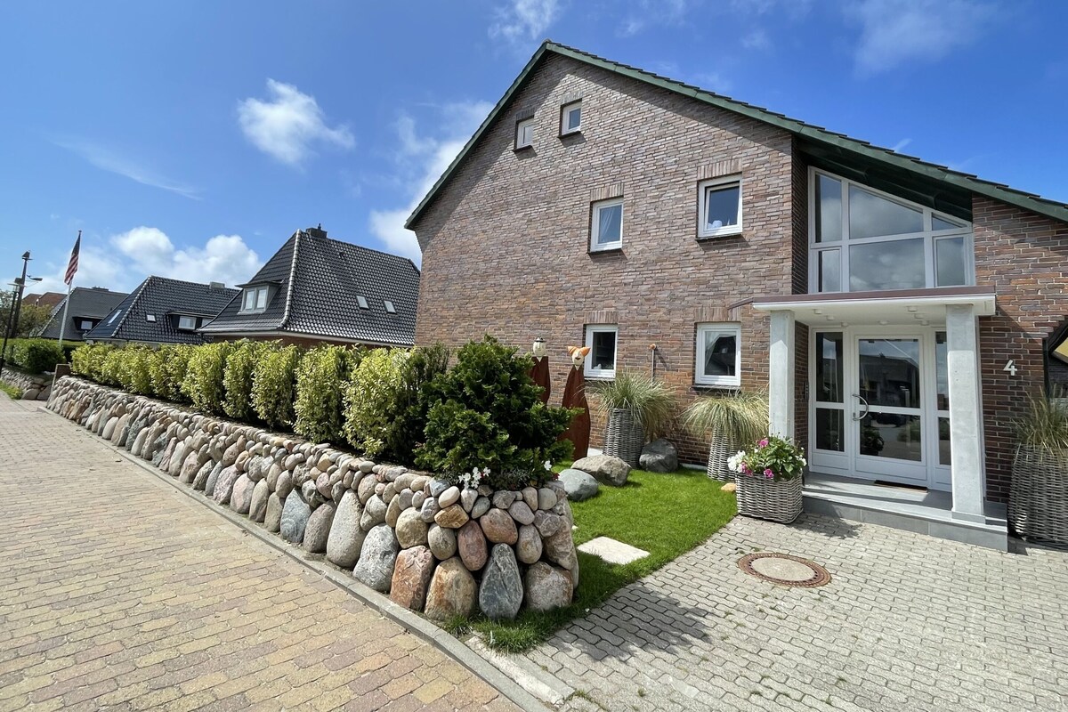 A modern two-story brick house with a stone wall and a paved driveway.