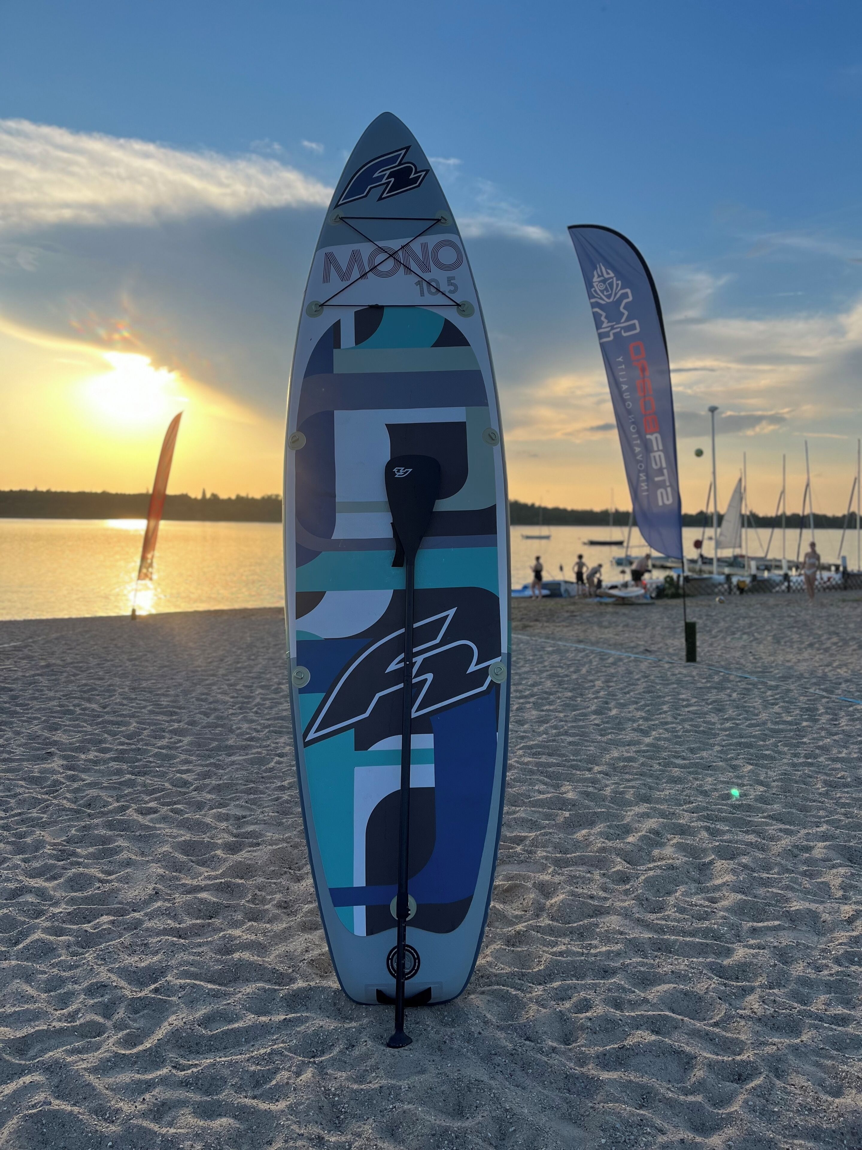 A surfboard on a sandy beach with a sunset in the background.