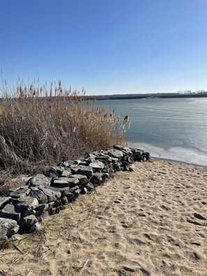 Une plage de sable avec un mur de pierres et de hautes herbes.