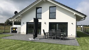 A modern house with a patio, outdoor seating, and a garage. - Vacation home Hilde on the lake with private beach for 4 adults, fireplace, boat and sauna (Löbnitz)