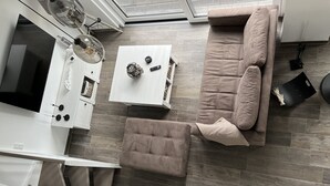 A modern living room with a sectional sofa, a white coffee table, and a TV mounted on the wall. - Vacation home Hilde on the lake with private beach for 4 adults, fireplace, boat and sauna (Löbnitz)