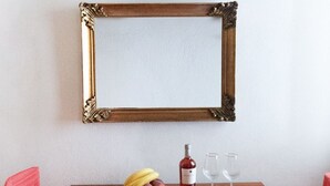 Un comedor con una mesa redonda, sillas rojas, una botella de vino y dos copas.