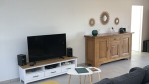 Un salon moderne avec un grand téléviseur à écran plat, un meuble en bois et un canapé gris.