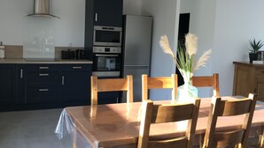 Une cuisine moderne avec des meubles de couleur sombre, une hotte de cuisson en acier inoxydable et un four encastré.