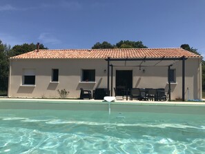 A building with a tiled roof, a pool, and outdoor seating.