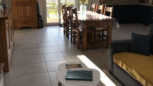 Un vaste espace de vie comprenant une table à manger, des chaises, un canapé et une petite table avec un livre.