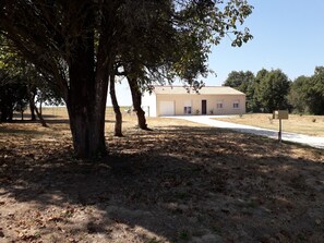 Un bâtiment doté d’un toit plat et d’une porte de garage, entouré d’arbres et d’une zone herbeuse.