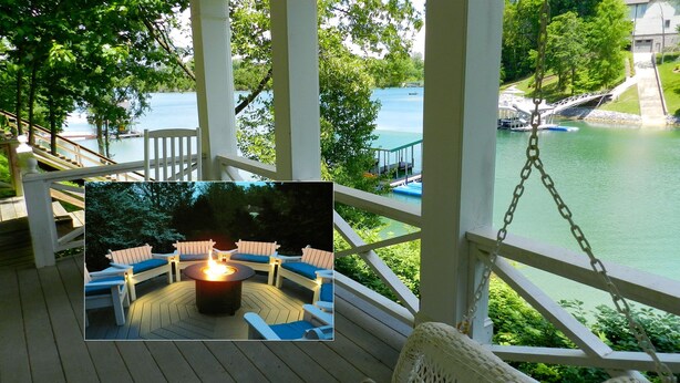 Eine Holzterrasse mit Sitzgelegenheiten im Freien und einer Feuerstelle, mit Blick auf einen See mit Booten und einer Brücke.