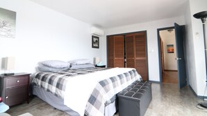 Een slaapkamer met een bed, nachtkastje, lamp en een kledingkast.