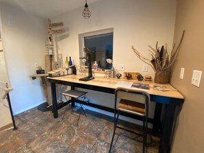 Una cocina con mostrador de madera, un fregadero y una ventana. Hay sillas y una mesa pequeña.
