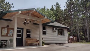 A cabin with a covered porch, a bench, and a table with chairs. - Peaceful Cottage on Lake Michigan (Two Rivers)