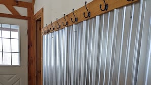 A room with a wooden bench, a metal wall with vertical ridges, and a wooden ceiling beam. - Countryside Cabin on 40 Private Acres Along Johnson Creek (Lyndonville)