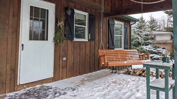 A wooden cabin with a porch, a bench, a door, and a window. - Countryside Cabin on 40 Private Acres Along Johnson Creek (Lyndonville)
