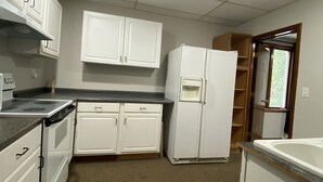 A compact kitchen with white cabinets, a built-in stove, and a refrigerator. - Outlaw Lodge (McCoy Floor 2nd)ATV,SXS, MX Offroad lodging (Iaeger)