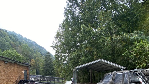 A gravel driveway leading to a covered structure with a vehicle parked nearby. - Outlaw Lodge (McCoy Floor 2nd)ATV,SXS, MX Offroad lodging (Iaeger)
