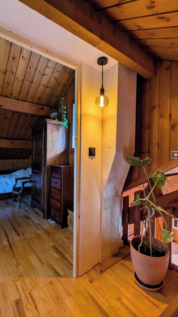 A wooden interior with a bed, a desk, and a potted plant. - Authentic chalet in the heart of Serre Chevalier, 300m from the slopes (Saint-Chaffrey)