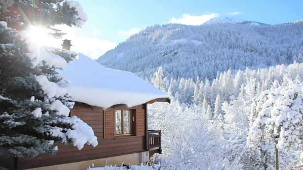 A wooden cabin with a snow-covered roof, surrounded by a forested mountain landscape. - Authentic chalet in the heart of Serre Chevalier, 300m from the slopes (Saint-Chaffrey)