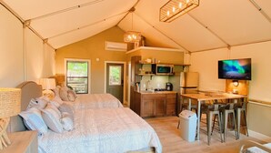 A tented accommodation with a bed, kitchenette, and a TV. - #13 Son's Geronimo - Birdhouse Cabin (Seguin)