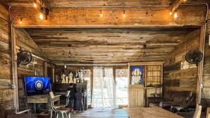 A rustic wooden interior with a long dining table, leather couches, and a television. - #13 Son's Geronimo - Birdhouse Cabin (Seguin)