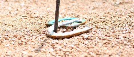 A close-up of a metal object with a blue ring on a sandy surface.