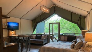 A tented accommodation with a bed, desk, and TV. - #13 Son's Geronimo - Birdhouse Cabin (Seguin)