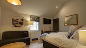 A bedroom with a bed, a desk, a chair, a sofa, and a lamp. - The Temple Inn (Bristol)