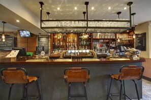Un espace bar comprenant un comptoir, des tabourets et une variété de bouteilles et de verres.