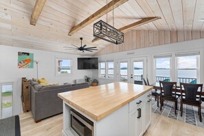 Une cuisine moderne dotée d’un îlot central en bois, d’un four encastré et d’un coin repas offrant une vue sur le lac.