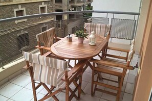 A wooden table and chairs on a balcony with a view of buildings. - Cozy and Modern Apartment Centrally Located (Volos)