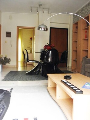 A modern living room with a wooden coffee table, black chairs, a sofa, and a lamp.
