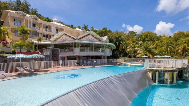 Ein Hotel mit großem Pool, Wasserrutsche und einem mehrstöckigen Gebäude mit Balkonen.