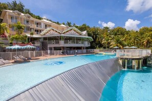 A hotel with a large pool, a water slide, and a multi-story building with balconies.