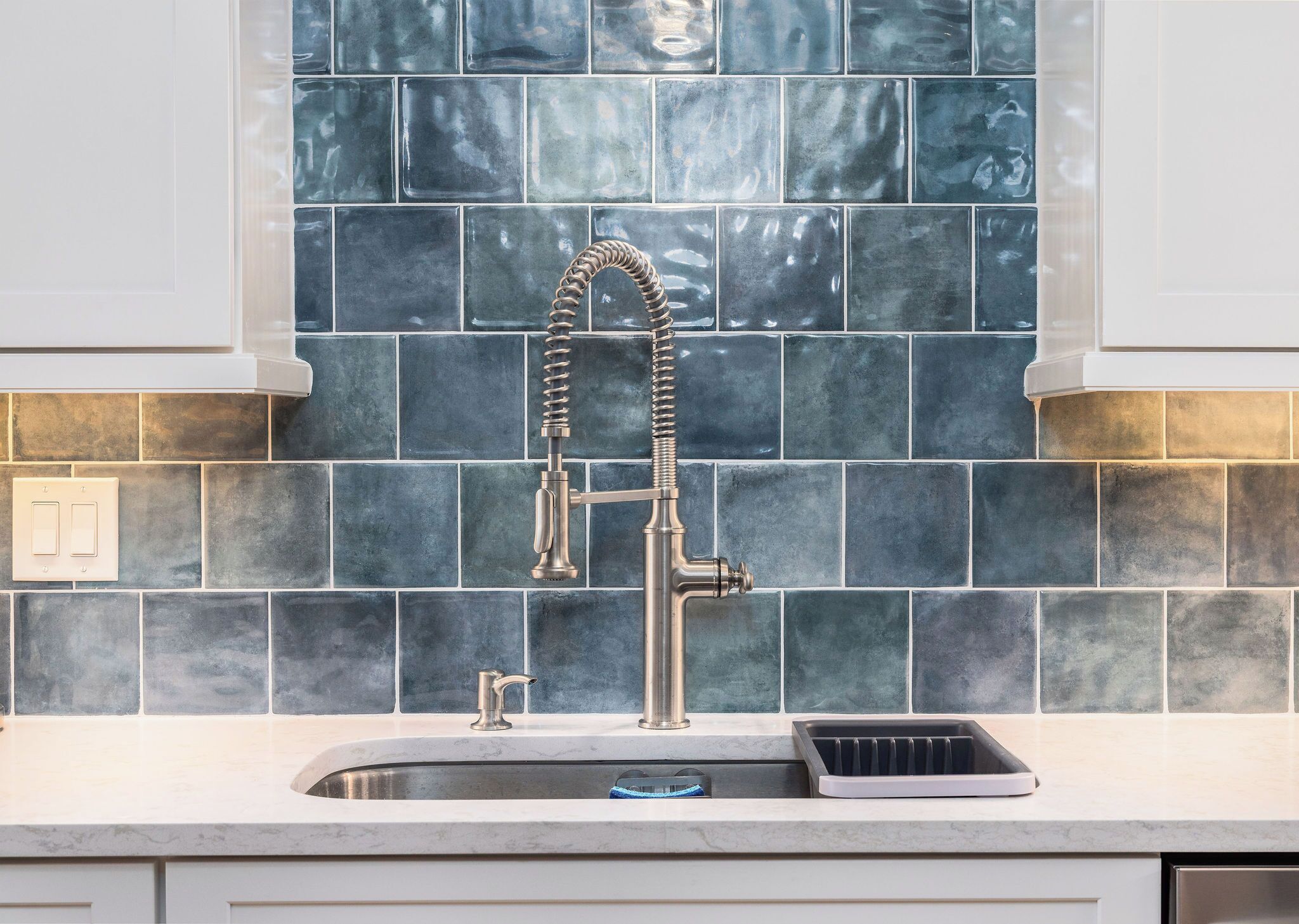 A kitchen with a stainless steel faucet, a sink, and a tiled backsplash.