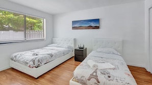 A bedroom with two beds, a nightstand, a window with blinds, and a picture on the wall. - Spacious and Bright 2bed, washer/dryer, back yard (Delray Beach)