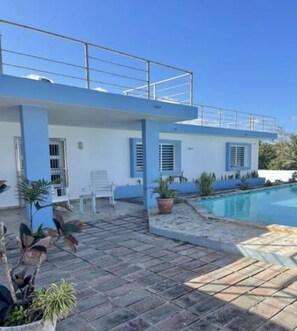 Un edificio moderno con piscina, mobiliario exterior y plantas en macetas.