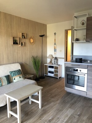 Una cucina moderna con forno integrato, pavimento in legno e zona pranzo con una panca e un tavolo.