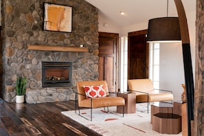 A cozy living room with a stone wall, fireplace, and modern furniture.