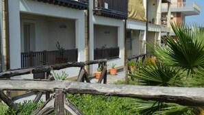 A residential building with balconies, potted plants, and a wooden fence. - Accommodation Mediterraneo Verde - Marzamemi (Marzamemi)