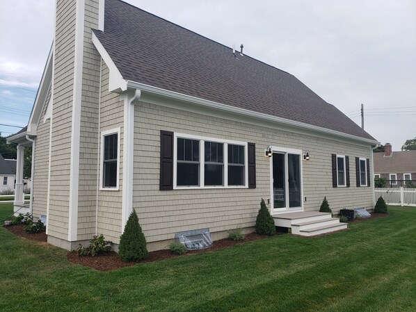 A single-story house with a gabled roof, white siding, and a front porch with steps. - Bass River Home (South Yarmouth)