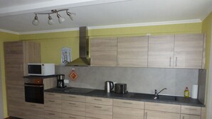 A kitchen with wooden cabinets, a microwave, a toaster, and a sink. - Vacation apartment in the Moselle valley, near the Middle Moselle (Raversbeuren)