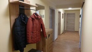 A hallway with wooden benches and a coat rack holding two jackets. - Vacation apartment in the Moselle valley, near the Middle Moselle (Raversbeuren)