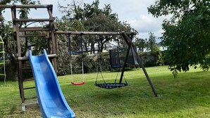 A playground with a blue slide, swings, and a climbing structure. - Vacation apartment in the Moselle valley, near the Middle Moselle (Raversbeuren)