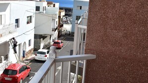 En balkon med udsigt over en gade med parkerede biler og bygninger.