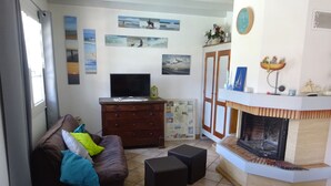 Een woonkamer met een bruine bank, een televisie, een open haard en wanddecoratie.