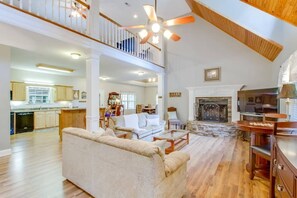 Cozy living area with a fireplace, dining table, and staircase leading to an upper level.