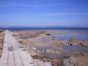 Una costa rocosa con un paseo pavimentado que conduce al agua.