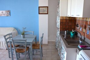 A compact kitchen with a sink, a stove, and a dining area with a table and chairs.