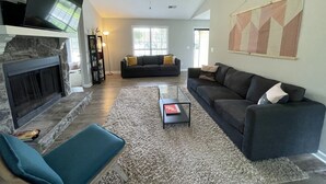 A living room with a fireplace, a sofa, a coffee table, and a TV. - Spacious 4 bedroom home near Charleston & beaches! (Ladson)
