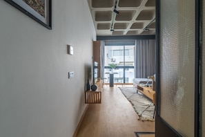 Stylish hallway leads to a cozy living area with a sofa, coffee table, and large window offering a view.